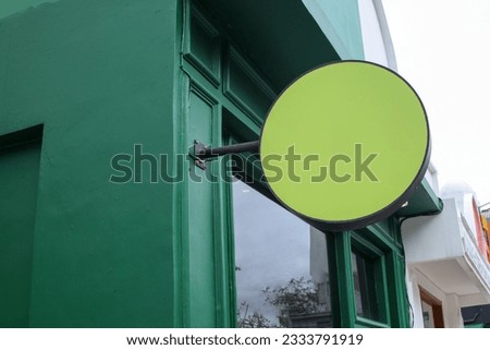 Blank rounded store signage for mockup. Rounded signboard hanging mounted on the green wall. Signboard for logo presentation. Cafe restaurant bar badge on green color.