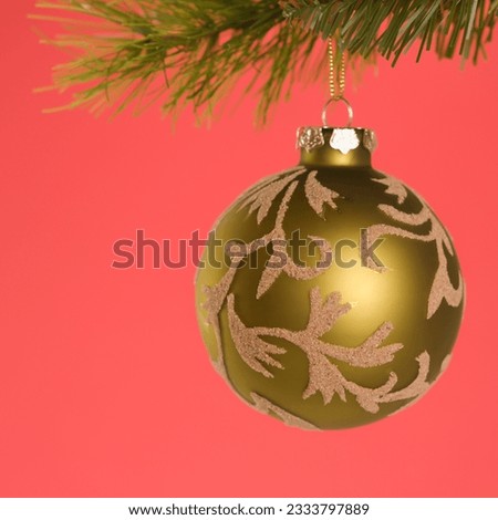 Still life of gold Christmas ornament hanging from pine branch.