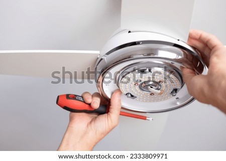 Close up on electrician man 's hands installing a paddle fan on the ceiling at home Royalty-Free Stock Photo #2333809971