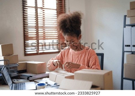 Startup young african american millennial packing products from online buyer.
 Royalty-Free Stock Photo #2333825927