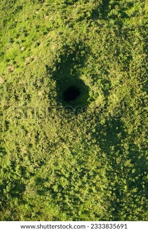 Aerial view of collapsed lava tube surrounded by green trees in Maui, Hawaii.