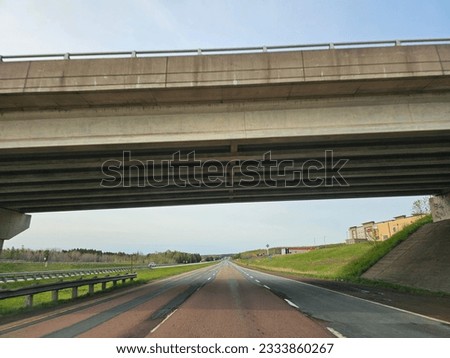 An open divided highway going under an overpass on a cloudy spring morning.