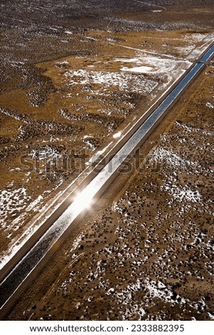 Aerial landscape of water canal running though rural Colorado with sun reflection.
