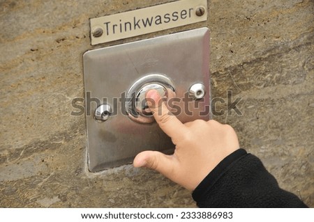 child finger pressing button with the german word potable water