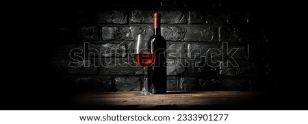 Bottle and glass of wine near black wall