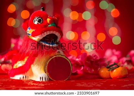 Chinese new year decorations, miniature dancing lion and mandarin orange on red glitter background.