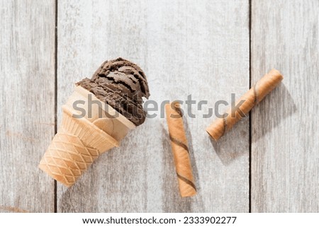 Top view chocolate ice cream in waffle cone on white vintage wooden background.