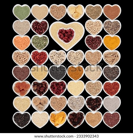 Large dried superfood collection in heart shaped porcelain china bowls forming an abstract background over black background. High in minerals, vitamins and antioxidants.