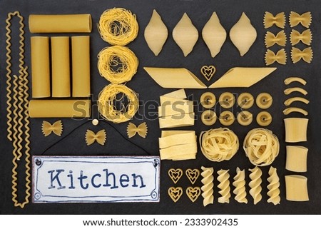 Dried italian pasta food selection with old metal kitchen sign forming an abstract background over slate.