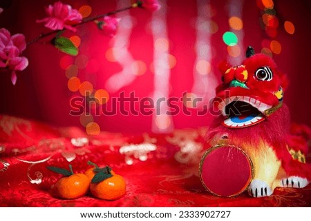 Chinese new year festival decorations, miniature dancing lion and mandarin orange on red glitter background.