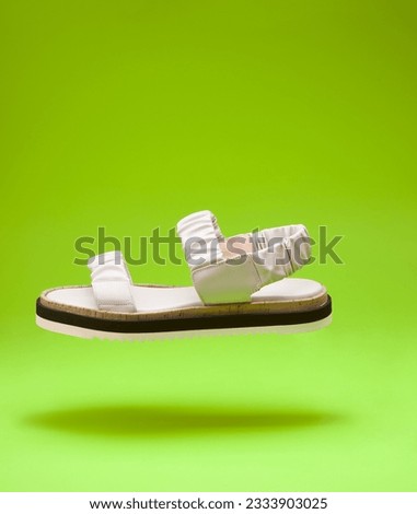 A modern flying pastel women's sandal from wrinkled design leather with three-colored soles isolated on a bright yellow background with copy space. Levitation concept, lifestyle product photo.