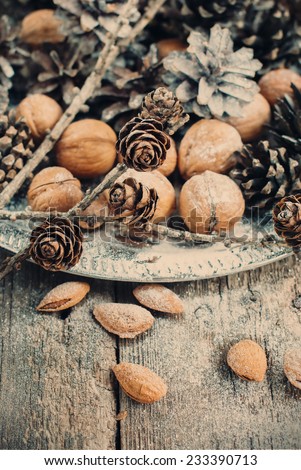  Christmas Tray with Pine cones, Walnuts, Almonds, Nuts on Wooden Background, holiday decoration, toning