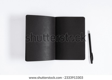 Flat lay top view of blank open black notebook with pen isolated on white background. Empty black notepad