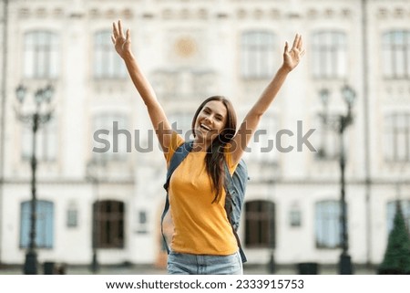 Successful Student. Joyful College Female Raising Arms And Celebrating Success Outdoors After Getting Tuition And Educational Grant For Learning Abroad, Posing With Backpack Near University Outside Royalty-Free Stock Photo #2333915753