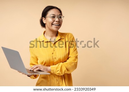 Beautiful African American woman wearing eyeglasses holding laptop computer, communication, working online, looking at distance. Technology, video conference concept