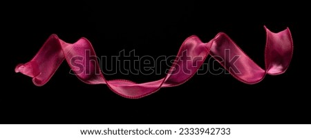 Red rose ribbon long straight fly in air with curve roll shiny. Red yellow ribbon for present gift birthday party to wrap around decorate, curl curve long straight. Black background isolated Royalty-Free Stock Photo #2333942733