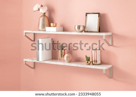 white shelves hanging to a pink wall with minimal gold color home decor accessories