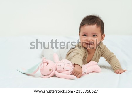 infant baby playing doll on a bed Royalty-Free Stock Photo #2333958627