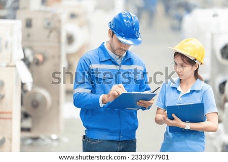 half body photo American engineer and female mechanic supervisor in warehouse checking product with listnote with radio communication Wear a helmet and uniform. In the plastic and steel industry