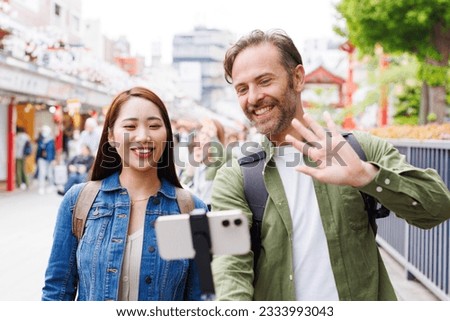 Caucasian man and Asian woman taking self photograph with mobile phone