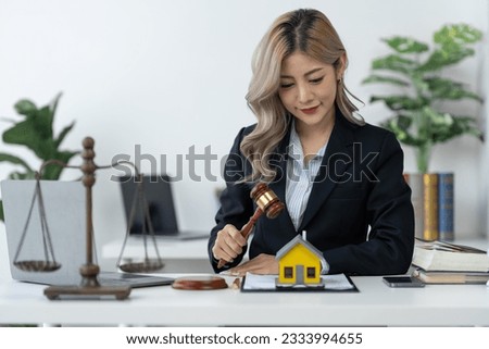 Businesswoman, lawyer, legal consultant sitting at work holding hammer of justice with business contract documents. housing project agreement Real estate on the office desk.