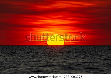 Dramatic sunset on the horizon at Mindil Beach, somewhat resembling the Australian Aboriginal flag. Darwin, Australia.