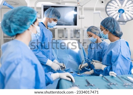 Group of medical team urgently doing surgical operation and helping patient in theater at hospital. Medical team performing surgical operation in a bright modern operating room Royalty-Free Stock Photo #2334017471