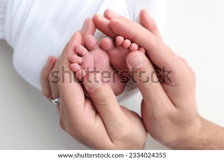 The palms of the father, the mother are holding the foot of the newborn baby on white background. Feet of the newborn on the palms of the parents. Photography of a child's toes, heels and feet.