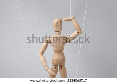 One wooden puppet with strings on light grey background
