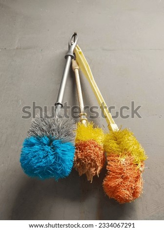 three used toilet brushes hanging from the wall