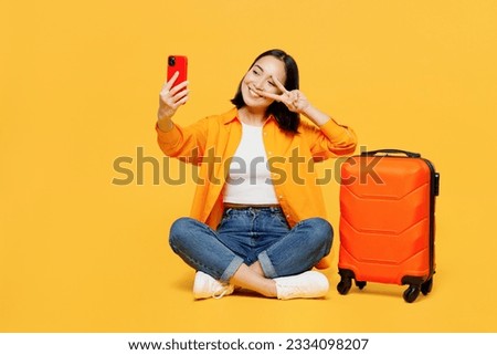 Young woman wears summer clothes sit suitcase do selfie shot on mobile cell phone isolated on plain yellow background. Tourist travel abroad in free time rest getaway. Air flight trip journey concept