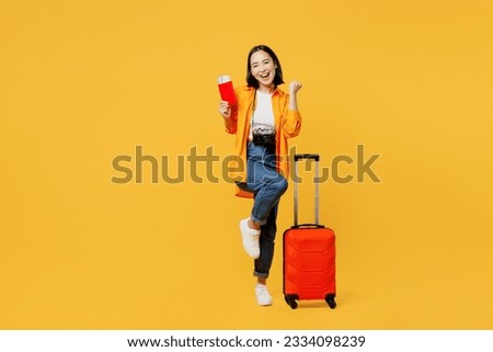 Young woman wears summer clothes hold passport ticket suitcase do winner gesture isolated on plain yellow background. Tourist travel abroad in free time rest getaway. Air flight trip journey concept Royalty-Free Stock Photo #2334098239
