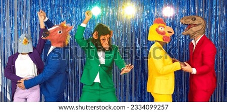Group of funny people with animal heads are dancing and having fun at crazy costume party. Friends in colorful clothes and in absurd masks have fun against background of shiny foil curtain. Banner.