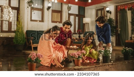 Portrait of an Indian Family Celebrating Divali by Putting Lamps in Their Backyard. Happy Young Parents and Their Exited Children Participating in Hindu Religious Festivities, Festival of Lights Royalty-Free Stock Photo #2334107365