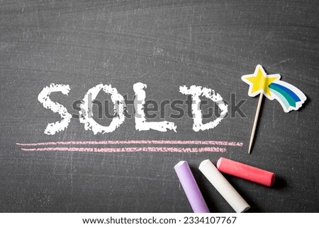 SOLD. Colored pieces of chalk on a dark chalkboard background.