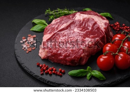 Fresh, raw beef steak with salt, spices and herbs on a dark textured background Royalty-Free Stock Photo #2334108503