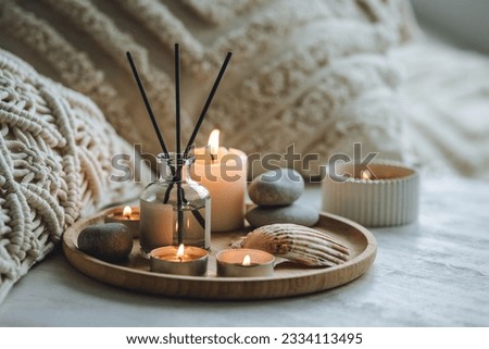 Apartment natural aroma diffusor with sea breeze fragrance. Burning candles on bamboo tray, cozy home atmosphere. Relaxation, detention zone in the living or bedroom. Stones as decor Royalty-Free Stock Photo #2334113495