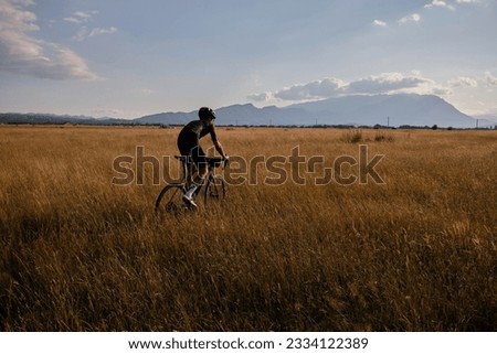 Male cyclist wearing cycling kit and helmet riding on the road a gravel bike at sunset.Sports motivation image.