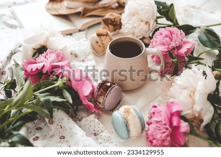 Cup of tea, macaroons and peonies, flat lay top view. good morning concept.