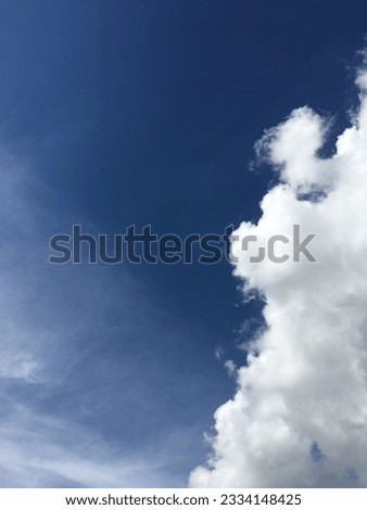 The background of a summer sky is a stunning sight, with white fluffy clouds set against a brilliant blue hue. The tranquil sunlight of spring creates a clear and beautiful cloudy scene. 