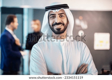 Emirati Arab at office with colleagues workmates people at background. Arabic man in Kandura dish dash at corporate business location Royalty-Free Stock Photo #2334151119