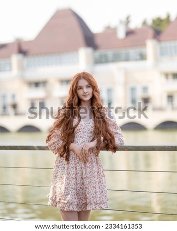 Red-haired girl on the background of the river and ancient buildings