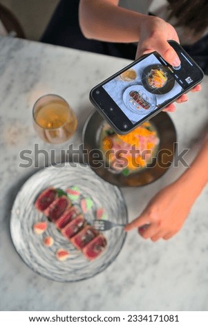 Content Creator Capturing Food Photos at Bustling Restaurant for Social Media