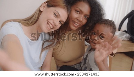Happy young homosexual female gay lesbian couple with son toddler baby boy is making taking selfie together or video call to friends or relatives in a living room at home, Concept of LGBTQ+ Royalty-Free Stock Photo #2334171435