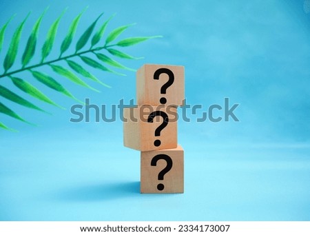 Three wooden cubes with a question mark over a beautiful blue background with copy space. Trouble and confusion.