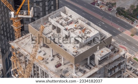 Tower cranes working on the construction site of new skyscraper of the monolithic office high-rise building aerial timelapse. Building progress in Dubai financial district