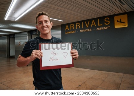 A young happy Hispanic man holding a sign with Welcome my love text at the airport