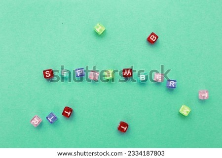 inscription September made by multicolor plastic cubes on a green background