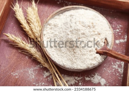 Bowl with wheat flour and spikelets on wooden tray, closeup Royalty-Free Stock Photo #2334188675