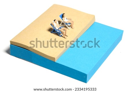 Creative miniature people toy figure photography. Sticky notes installation. A couple chilling out on beach bench at the beach. Isolated on white background. Image photo